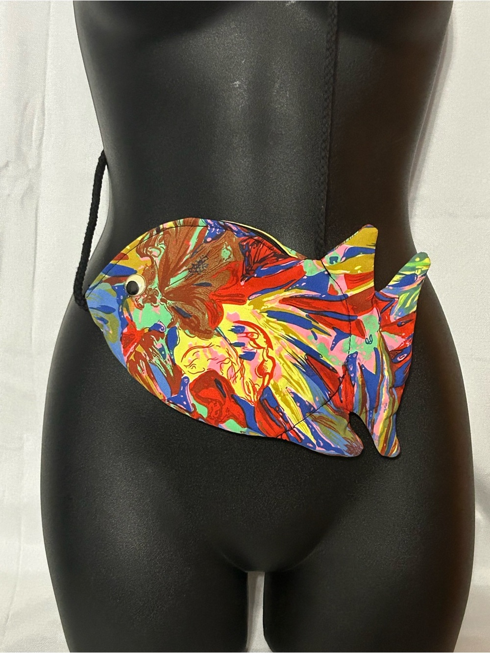 A colorful fish-shaped cross-body purse with a paint splatter design